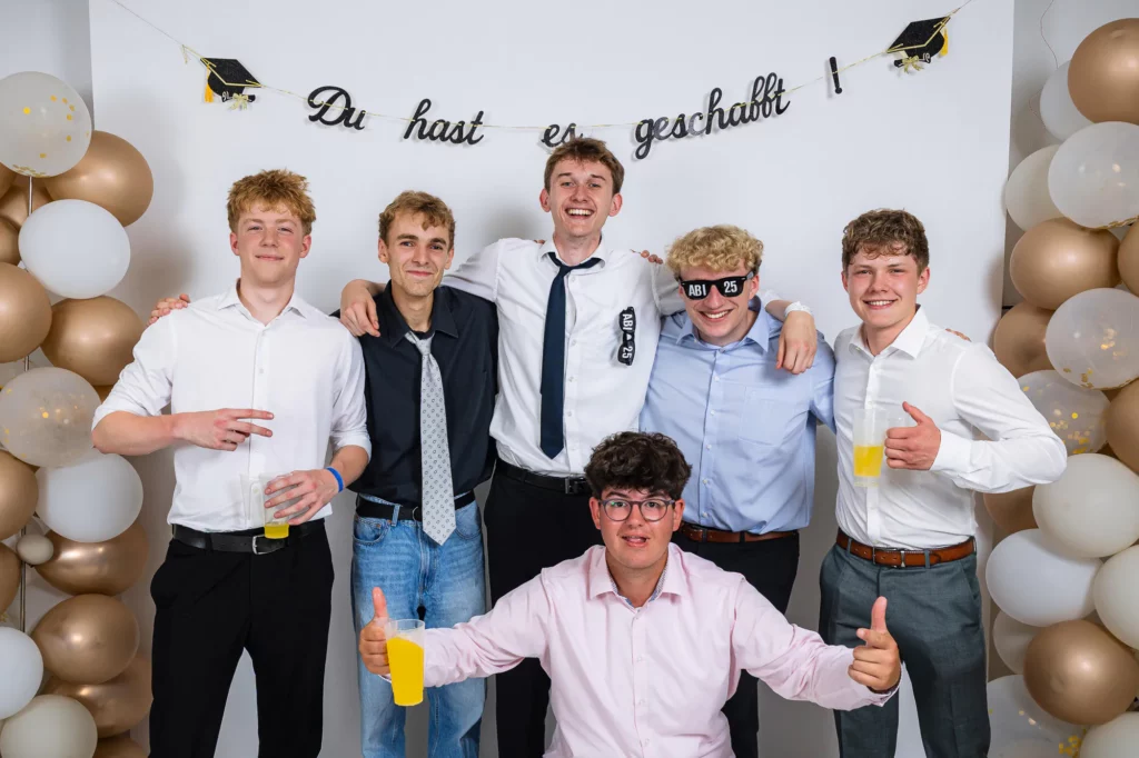 Fährhaus Kirschenland – Sechs Abiturienten in festlicher Kleidung posieren vor einer Fotowand mit Luftballons und dem Schriftzug Du hast es geschafft bei einem Abiball. | Jannes Romund Fotografie