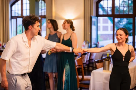 Fährhaus Kirschenland – Ein junges Paar tanzt bei einem Abiball in Stade, während im Hintergrund weitere Gäste in festlicher Abendgarderobe in einem Saal stehen. | Jannes Romund Fotografie