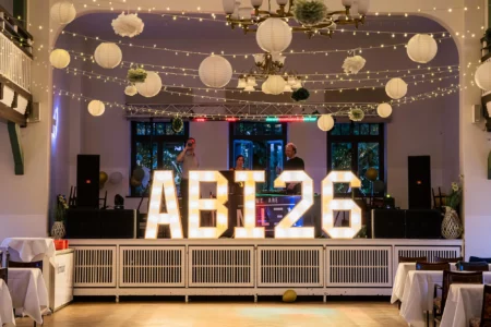 Fährhaus Kirschenland – Beleuchtete ABI 26 Buchstaben auf einer Bühne bei einem Abiball in Stade, dekoriert mit Lichterketten und weißen Papierlampions im Festsaal. | Jannes Romund Fotografie