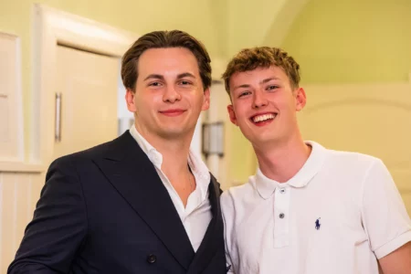 Fährhaus Kirschenland – Zwei junge Männer lächeln in die Kamera bei einem Abiball in Stade, einer trägt ein elegantes dunkles Sakko, der andere ein weißes Poloshirt. | Jannes Romund Fotografie