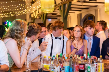 Fährhaus Kirschenland – Junge Abiturienten in festlicher Kleidung stehen an einer Bar bei einem Abiball in Stade und unterhalten sich in entspannter Atmosphäre. | Jannes Romund Fotografie