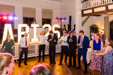 Fährhaus Kirschenland – Festliche Abiballfeier in Stade mit Absolventen vor leuchtenden ABI24-Buchstaben, DJ-Pult und stimmungsvoller Beleuchtung im Saal. | Jannes Romund Fotografie