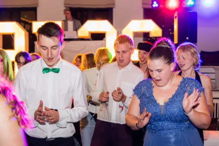 Fährhaus Kirschenland – Junge Abiturienten tanzen ausgelassen bei einem Abiball in Stade vor leuchtenden Zahlen, festliche Abendgarderobe und bunte Lichtstimmung. | Jannes Romund Fotografie