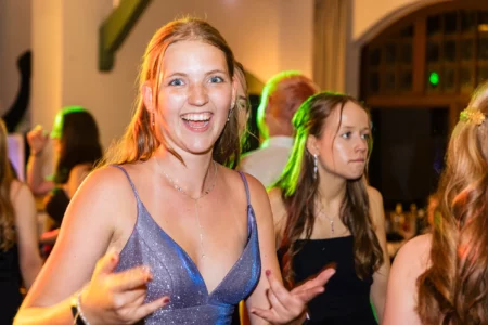 Fährhaus Kirschenland – Fröhliche Abiturientin in glitzerndem Abendkleid tanzt ausgelassen auf einem Abiball in Stade bei stimmungsvoller Beleuchtung. | Jannes Romund Fotografie