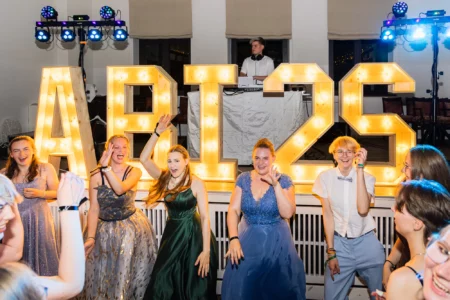 Fährhaus Kirschenland – Fröhliche Abiturienten feiern vor leuchtenden ABIS25-Buchstaben bei einem Abiball in Stade mit DJ im Hintergrund und festlicher Beleuchtung. | Jannes Romund Fotografie