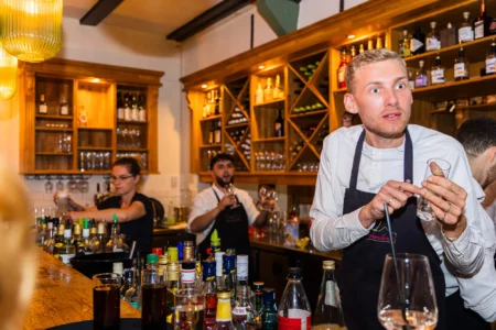 Fährhaus Kirschenland – Barkeeper in weißem Hemd und schwarzer Schürze bereitet Getränke hinter einer Bar bei einer Abiball Feier in Stade vor. | Jannes Romund Fotografie