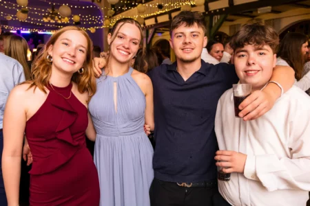 Fährhaus Kirschenland – Vier junge Abiturienten in festlicher Abendgarderobe lächeln gemeinsam bei einer Abiball-Feier in Stade vor einer Lichterkette. | Jannes Romund Fotografie