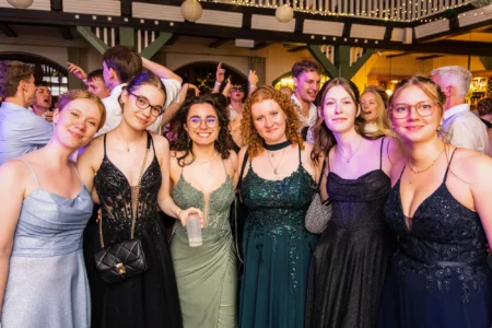 Fährhaus Kirschenland – Gruppe glücklicher Abiturientinnen in eleganten Abendkleidern beim Abiball in Stade, im Hintergrund feiern weitere Gäste auf der Tanzfläche. | Jannes Romund Fotografie
