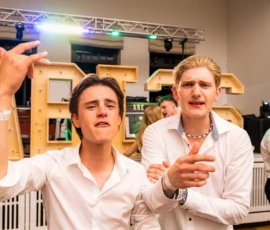 Fährhaus Kirschenland – Zwei Abiturienten in weißen Hemden feiern ausgelassen vor beleuchteten Holzbuchstaben auf einem Abiball in Stade mit DJ-Technik im Hintergrund. | Jannes Romund Fotografie