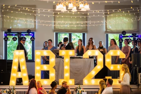 Fährhaus Kirschenland – Festliche Abiballfeier mit leuchtenden Buchstaben, Absolventen in Abendgarderobe und DJ-Pult in einem festlich geschmückten Saal in der Region Hamburg. | Jannes Romund Fotografie