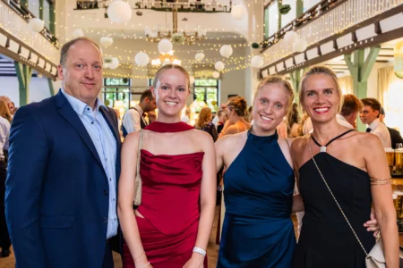 Fährhaus Kirschenland – Eine Familie posiert lächelnd bei einem Abiball in einer festlich beleuchteten Festhalle in Stade, Hamburg oder Buxtehude für ein Erinnerungsfoto. | Jannes Romund Fotografie