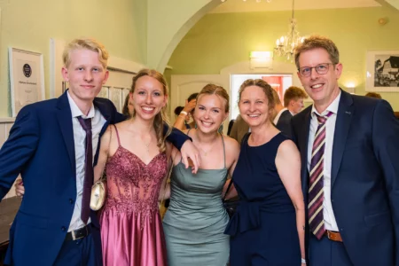 Fährhaus Kirschenland – Eine fröhliche Gruppe aus Abiturienten und Eltern posiert festlich gekleidet für ein Erinnerungsfoto bei einem Abiball in der Region Hamburg. | Jannes Romund Fotografie