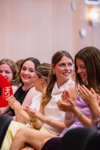 Abiballfotograf Stade – Gruppe junger Frauen applaudiert begeistert bei einer Veranstaltung, einige tragen elegante Kleider und Schmuck. | Jannes Romund Fotografie