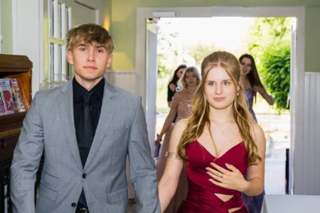 Fährhaus Kirschenland – Ein junges Paar in festlicher Abendgarderobe betritt bei einem Abiball den Saal, im Hintergrund sind weitere Gäste in eleganten Kleidern zu sehen. | Jannes Romund Fotografie