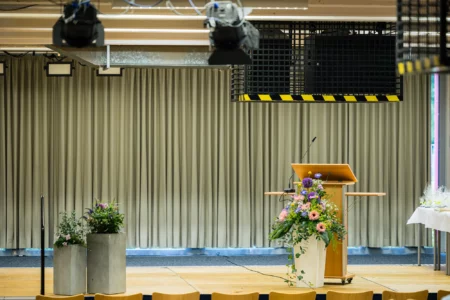 Abiballfotograf Stade – Ein dekorierter Rednerpult mit Blumenarrangements in einem Konferenzraum. | Jannes Romund Fotografie